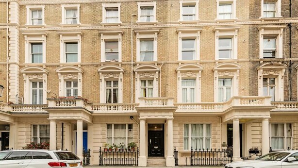 A row of townhouses with uniform brick facades, evenly spaced windows, and a central entrance with a black door. - Studio in Notting Hill (London)