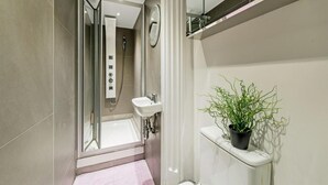 A modern bathroom with a shower, sink, and a potted plant. - Studio in Notting Hill (London)