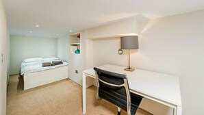 A bedroom with a bed, a desk, and a lamp. - Studio in Notting Hill (London)