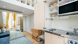 A compact kitchen with a built-in stove, a microwave, and shelves above. - Studio in Notting Hill (London)