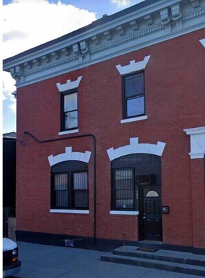 Classic two-story building with a symmetrical facade, featuring a central entrance and decorative moldings on the windows.