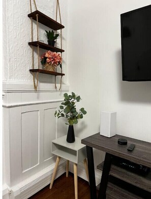 Relax in a serene space with a mounted TV, a small table, and a wooden shelf featuring a potted plant.