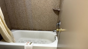 A bathroom with a bathtub, a toilet, and a shower curtain.