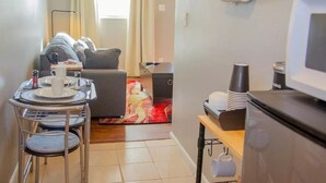 Um espaço de estar compacto com área de jantar, sofá, televisão e cozinha.