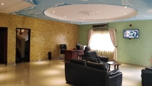 Amplia sala de estar con un mural en el techo, un sofá, un televisor y un escritorio con una computadora.