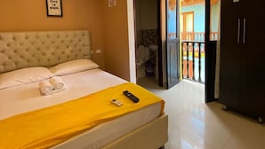A hotel room with a large bed, a yellow blanket, a remote control, and a view of the outside balcony. - Hotel en Getsemaní CL Con Desayuno  (Cartagena)