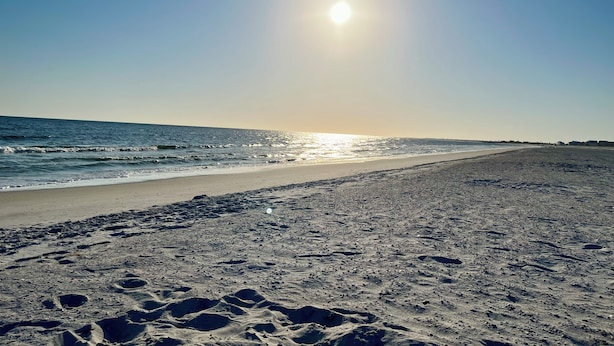 A beach with footprints leading to the water, a clear sky, and the sun reflecting on the sea. - The Sea Pony Gulf Views, King Suites & Walk to Beach in Mexico Beach Florida (Mexico Beach)