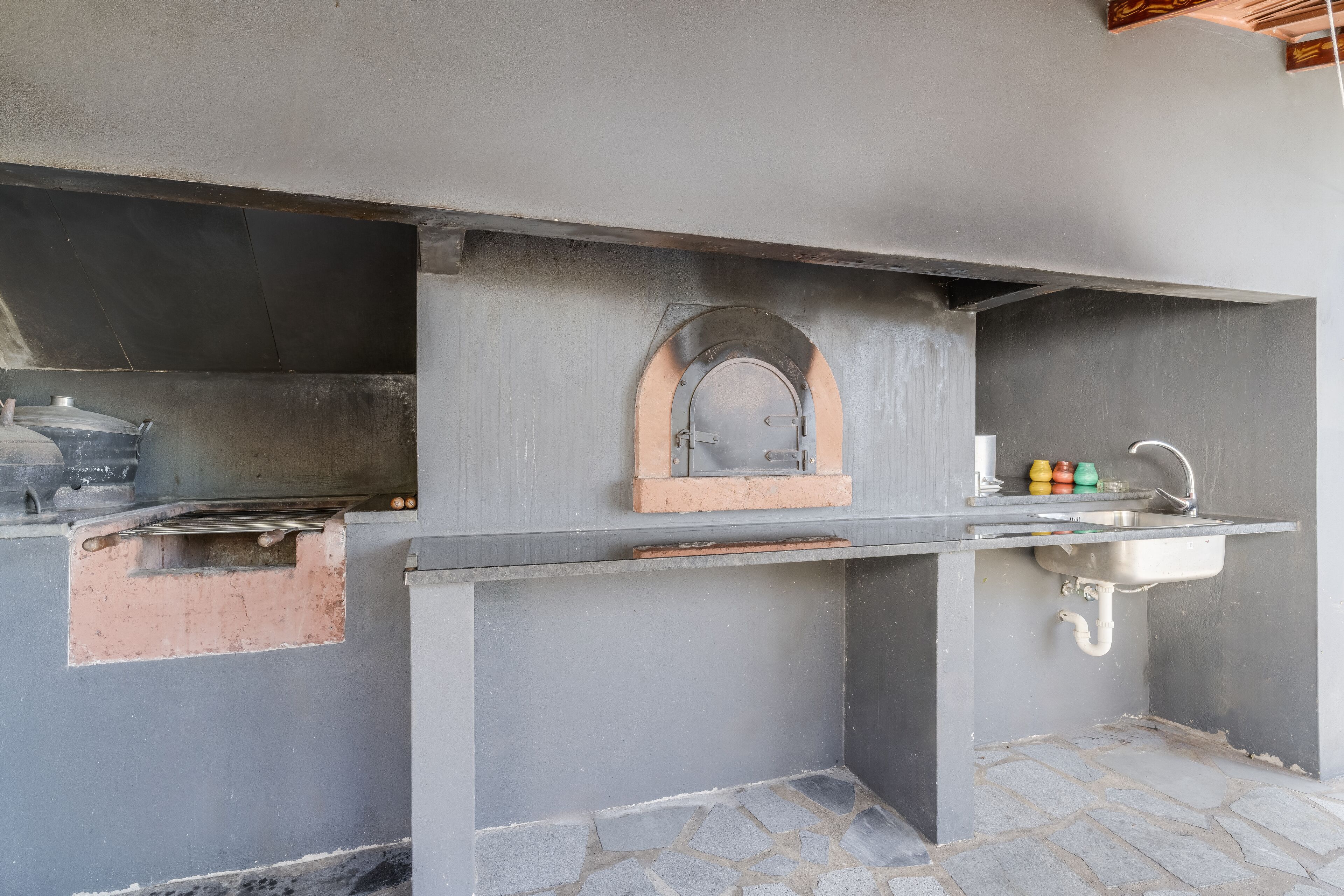 An outdoor kitchen with a stone countertop, a sink, and a built-in grill.
