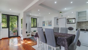 A modern kitchen with white cabinets, a microwave, and a dishwasher. - Villa Paixão (Machico)