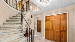 Un escalier avec une rampe, une porte en bois et un tapis à motifs sur le sol.