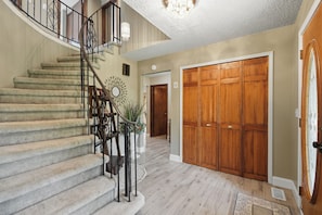 A staircase with a handrail, a chandelier, and a decorative mirror.