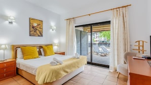 Een hotelkamer met een bed, bureau, stoel, lamp en uitzicht.