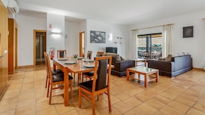 Een moderne woonkamer met een eethoek, met een bank, salontafel en een eettafel met stoelen.