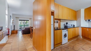 Een moderne keuken met houten kastjes, een wasmachine en een magnetron.