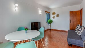 A modern living room with a round table, teal chairs, a grey sofa, and a TV. - Peaceful Flat in Lagos by LovelyStay (Lagos)