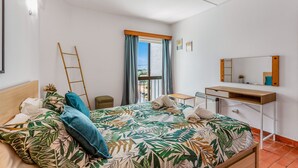 A hotel room with a bed, a small bedside table, a mirror, and a view of the outside. - Peaceful Flat in Lagos by LovelyStay (Lagos)