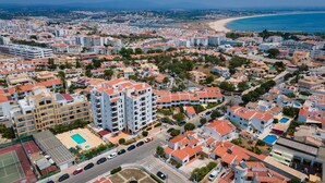 A coastal residential area with multiple-story buildings, a beach, and a road with cars. - Peaceful Flat in Lagos by LovelyStay (Lagos)