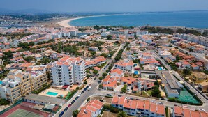 A coastal residential area with multi-story buildings, a beach, and a tennis court. - Peaceful Flat in Lagos by LovelyStay (Lagos)