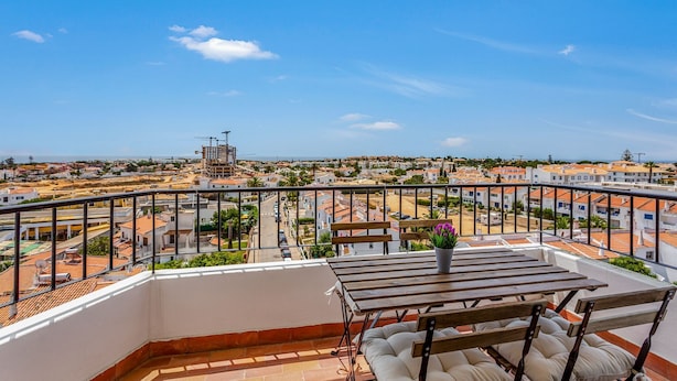 A balcony with a table and chairs, overlooking a residential area with buildings and a construction site. - Peaceful Flat in Lagos by LovelyStay (Lagos)