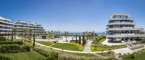 Un hôtel moderne à plusieurs étages, doté d’une piscine centrale et offrant une vue sur l’océan.