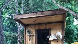 Une structure extérieure en bois dotée d’une porte, d’un petit porche et d’une chaise.