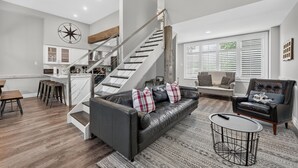 Ein zeitgemäßer Wohnraum mit Treppe, einer Ledersofa, einem Couchtisch und einem Essbereich.