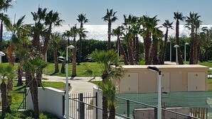 Een hotel met een omheind buitengebied, palmbomen en een heldere lucht.