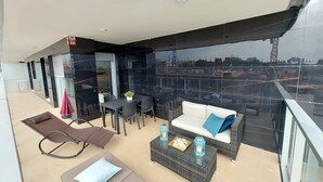 Een balkon met een eethoek, een bank en een loungestoel.