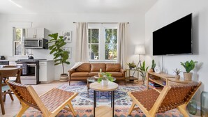 A modern living room with a sofa, two lounge chairs, a coffee table, and a flat-screen TV.