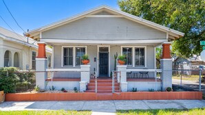A two-story house with a front porch, a black front door, and two potted plants on either side of the entrance.