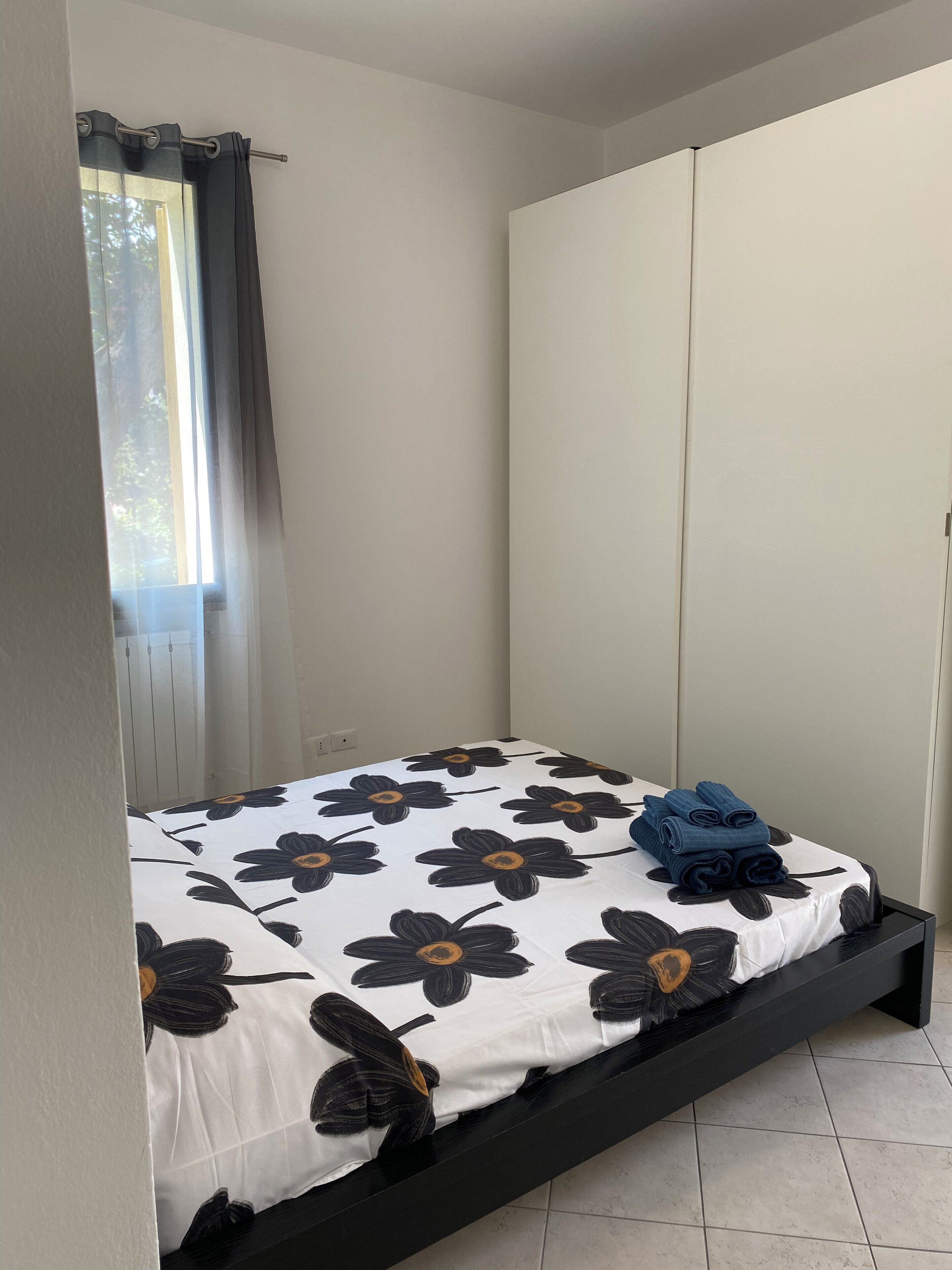 A bedroom with a bed, a wardrobe, and a window with curtains.
