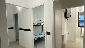 A hotel room with a bunk bed, white walls, and a tiled floor.