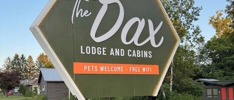 Señal de The Dax Lodge and Cabins que indica que se admiten mascotas y hay wifi gratuito.