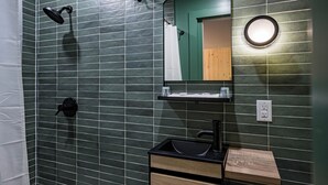 A bathroom with a shower, a sink with a mirror, and a towel rack.