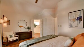 A bedroom with a bed, a dresser, a chair, a mirror, and a door leading to another room. - Shelby Farms Greenline Access: Modern Cordova Home (Cordova)