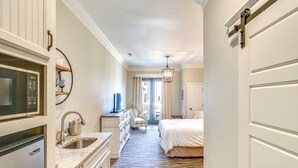 Habitación de hotel con kitchenette, cama, escritorio y vistas al exterior.