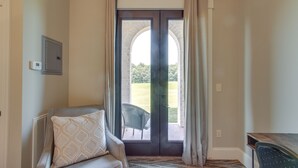 Habitación con puerta corrediza de vidrio que da a un espacio exterior, una silla, un radiador y una mesita.