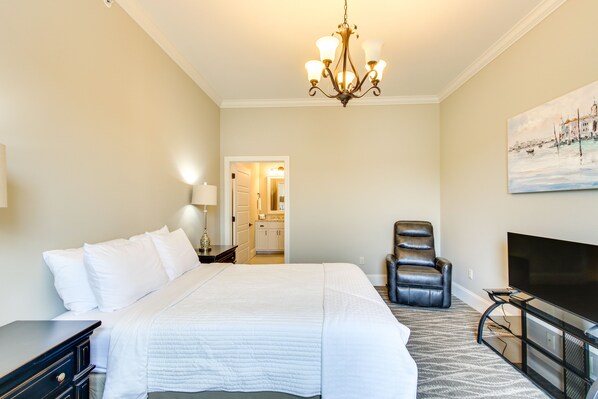 Una habitación de hotel con una cama grande, televisión, sillón de cuero y un cuadro en la pared.