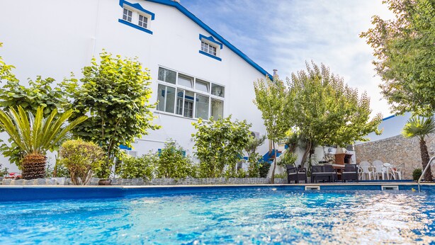 Una piscina amb un edifici blanc al fons.