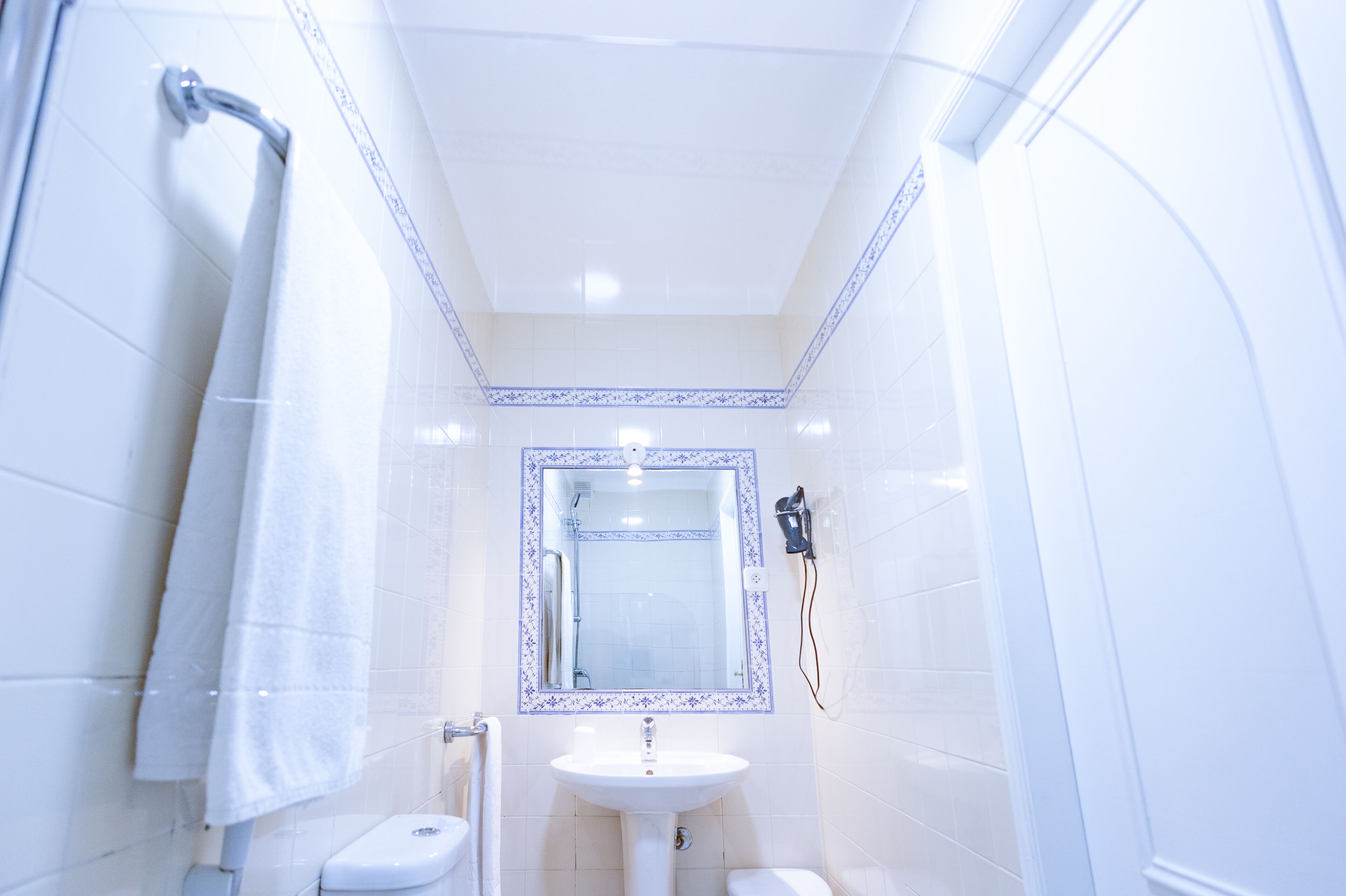 Un baño pequeño y blanco con lavamanos, inodoro y ducha.