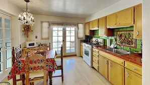 A spacious kitchen with wooden cabinets, a dining table, and a chandelier.