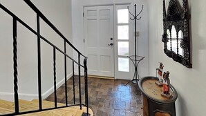 A staircase with black railings, a white door, and a wall-mounted decorative mirror.