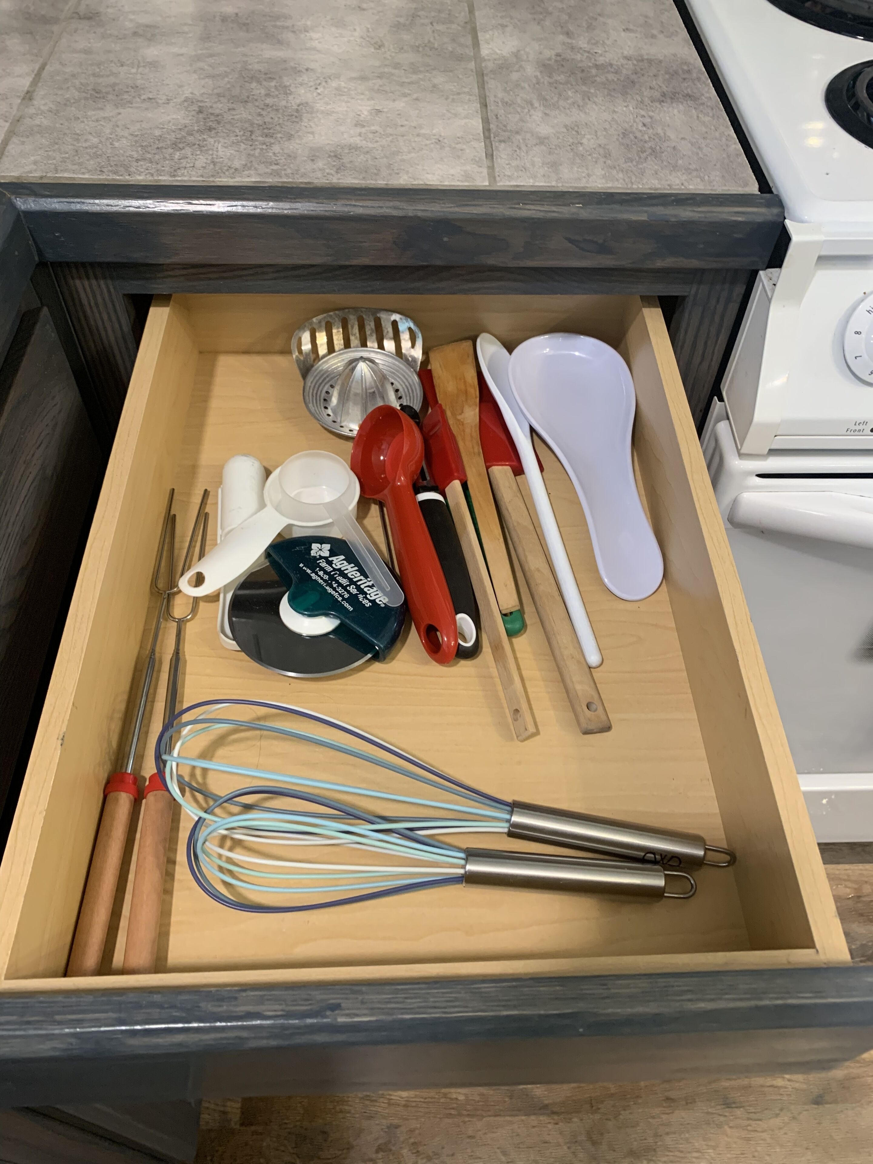A kitchen drawer containing various utensils and kitchen tools.
