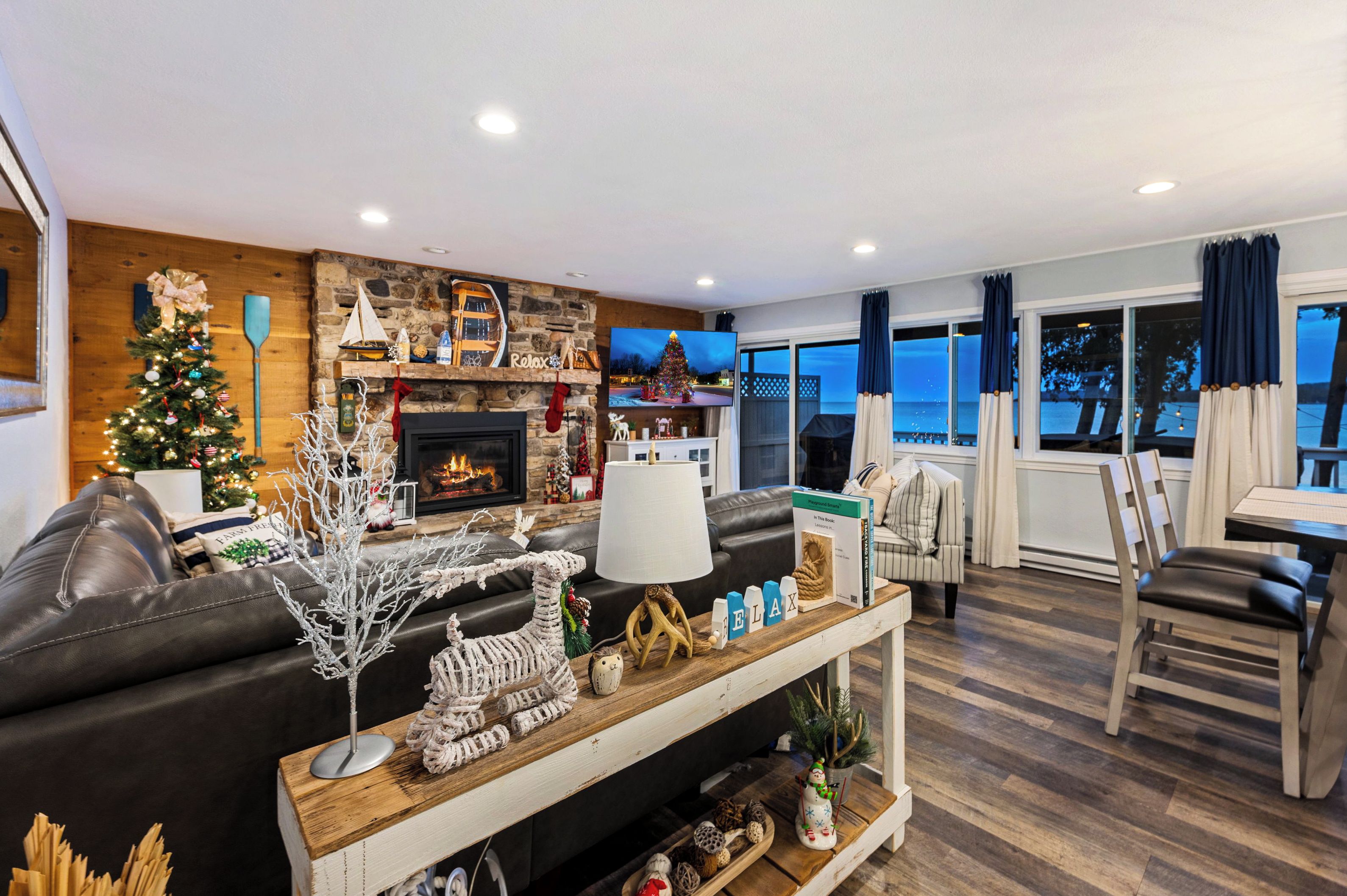 A wall of windows on the bay, with the fireplace and tree glowing through the holidays.