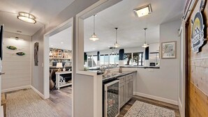 A modern kitchen with pendant lighting, a central island, and a view of the backyard. - Relax on the Bay — Kayaks, Hot Tub & Firepit Nights (Ellison Bay)