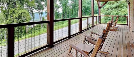 A covered outdoor seating area with wooden benches and a railing overlooking a road and greenery.
