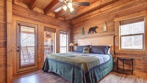 A wooden cabin bedroom with a bed, a ceiling fan, and a window. - Lasting Impressions by Jackson Mountain Rentals (Gatlinburg)