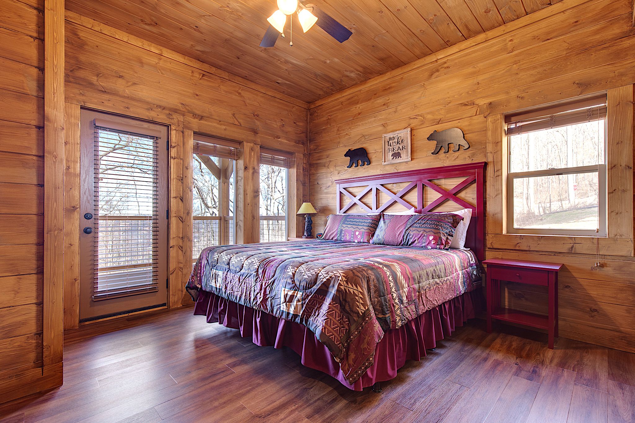 Quarto de cabana de madeira com cama, mesa de cabeceira e janela.