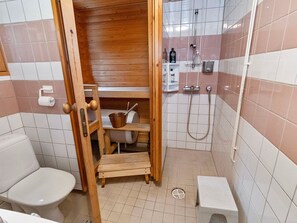 A compact bathroom with a wooden sauna, a toilet, a sink, and a shower. - Alakitkanranta by Interhome (Kuusamo)
