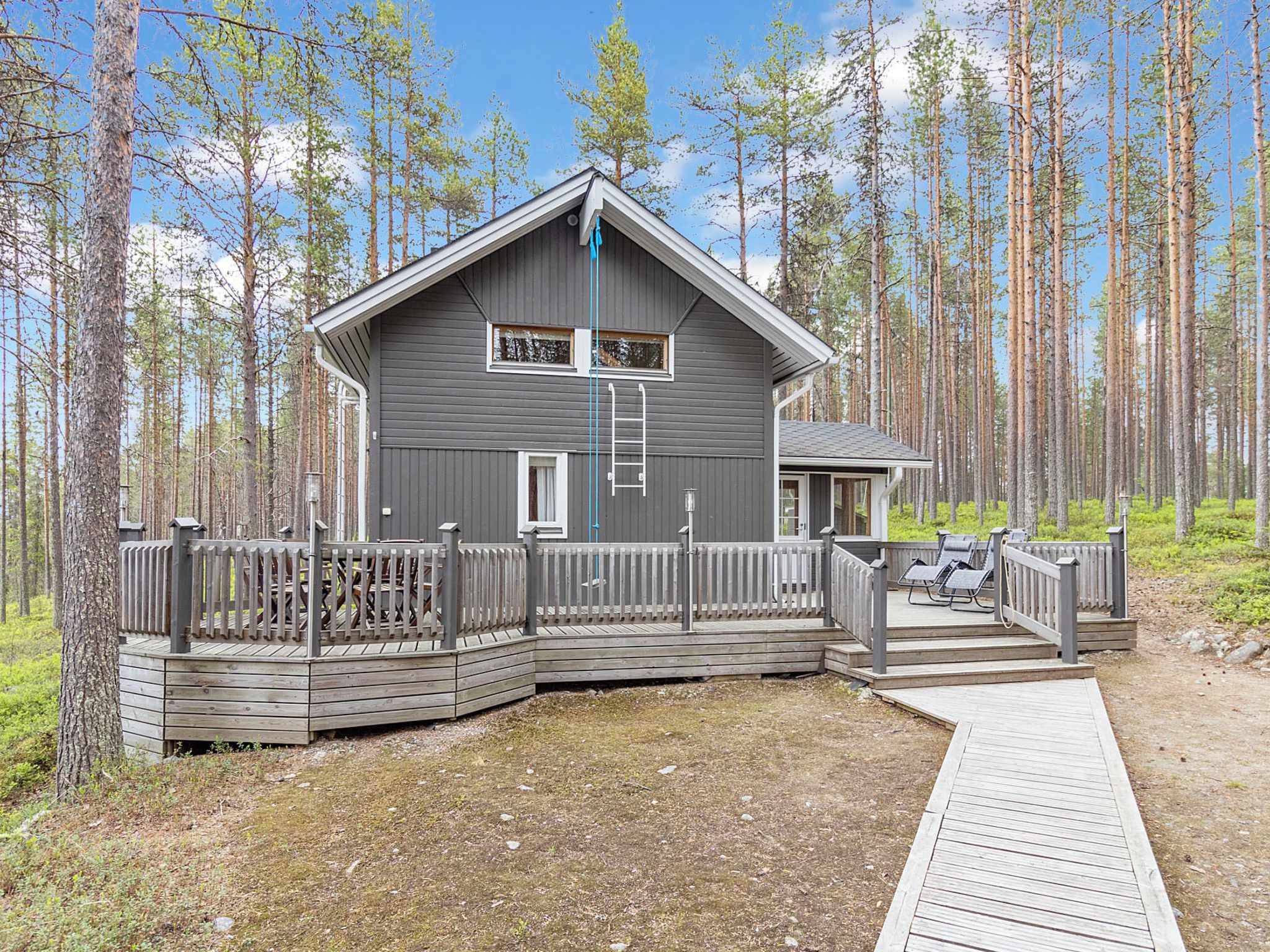 Mökki, jossa on terassi, ja jonka ympärillä on metsää.